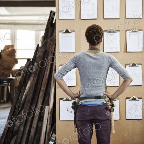 Woman factory worker checking project inventory in a woodworking factory.