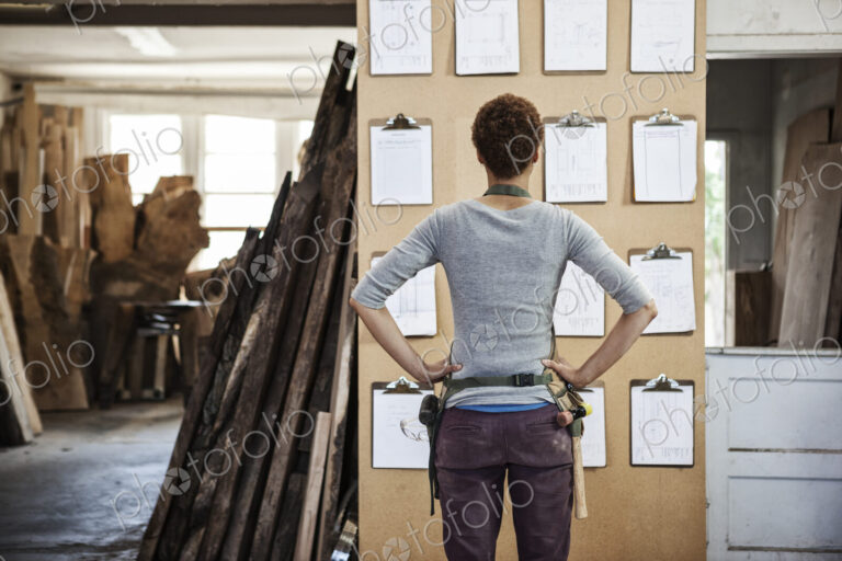Woman factory worker checking project inventory in a woodworking factory.