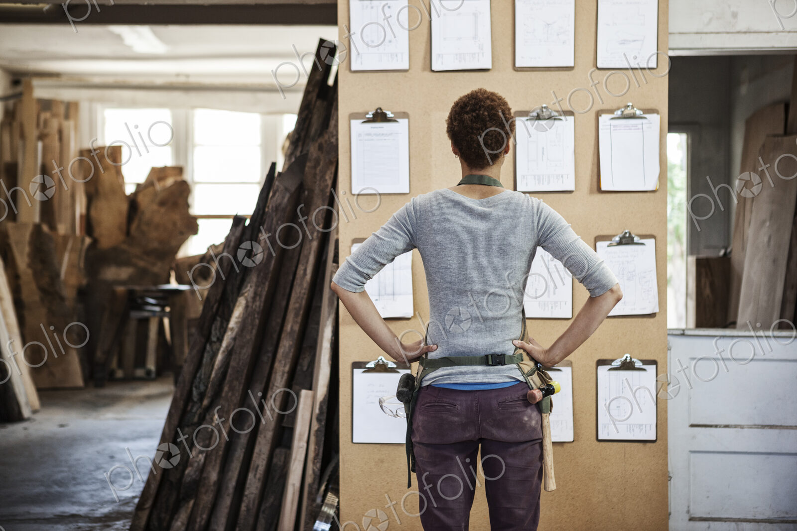 Woman factory worker checking project inventory in a woodworking factory.