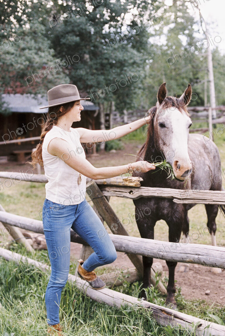 Woman feeding a horse in a paddock on a ranch.