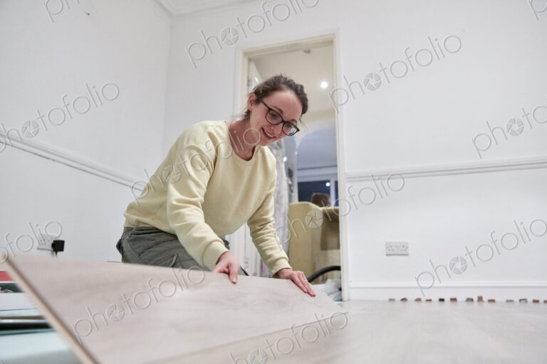 Woman fitting new wooden floor board