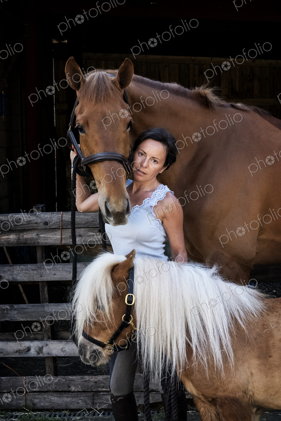 Woman holding a brown bay horse and a small Shetland pony by their reins.