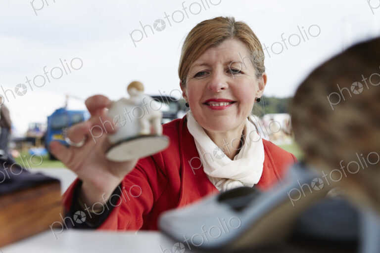 Woman holding a vintage porcelain figurine at flea market.