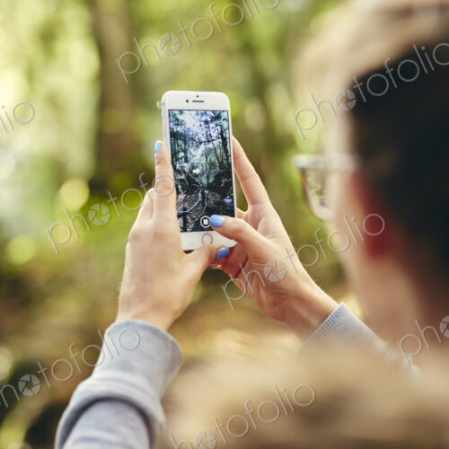 Woman holding up mobile phone outdoors in woodland. Woman holding up mobile phone outdoors in woodland.