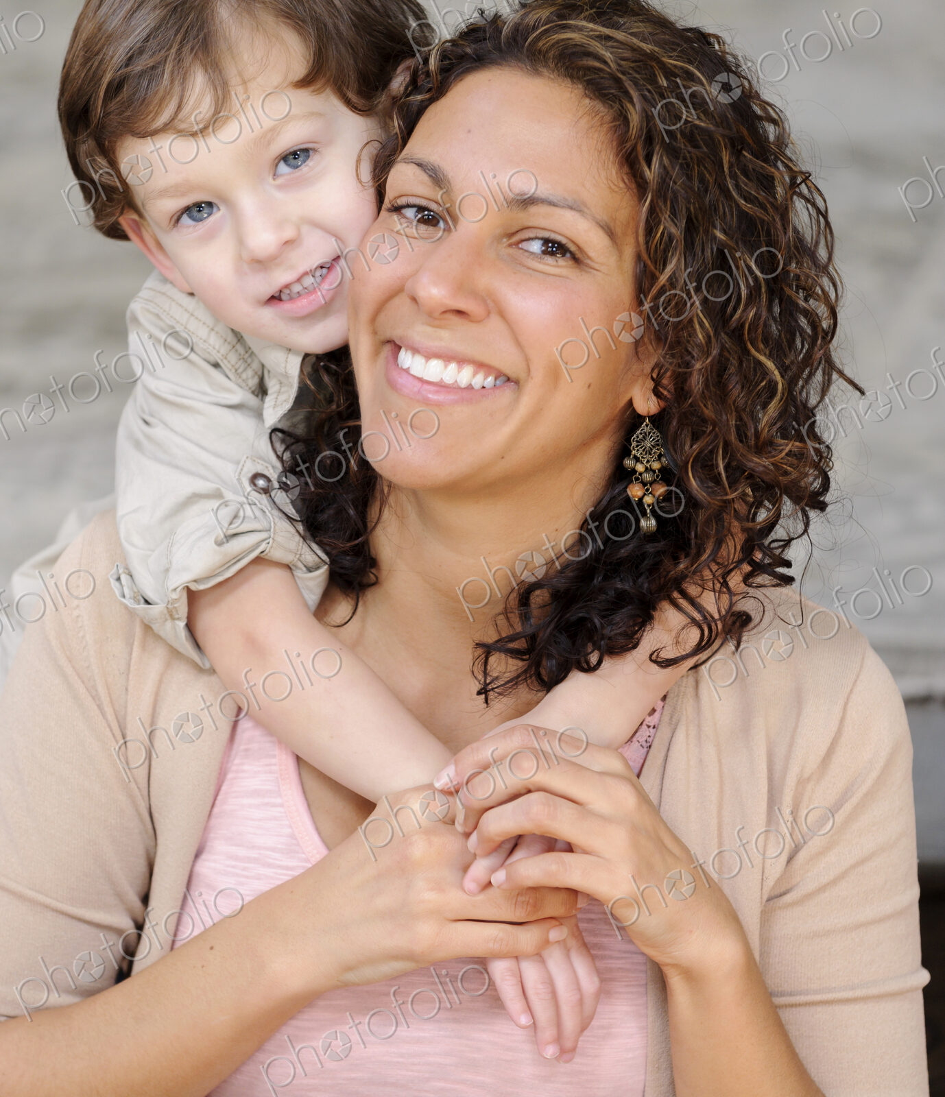 Woman hugging a boy, mother and sun laughing.