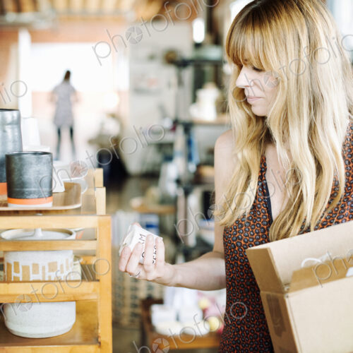 Woman in a shop, holding a small cardboard box with merchandise.