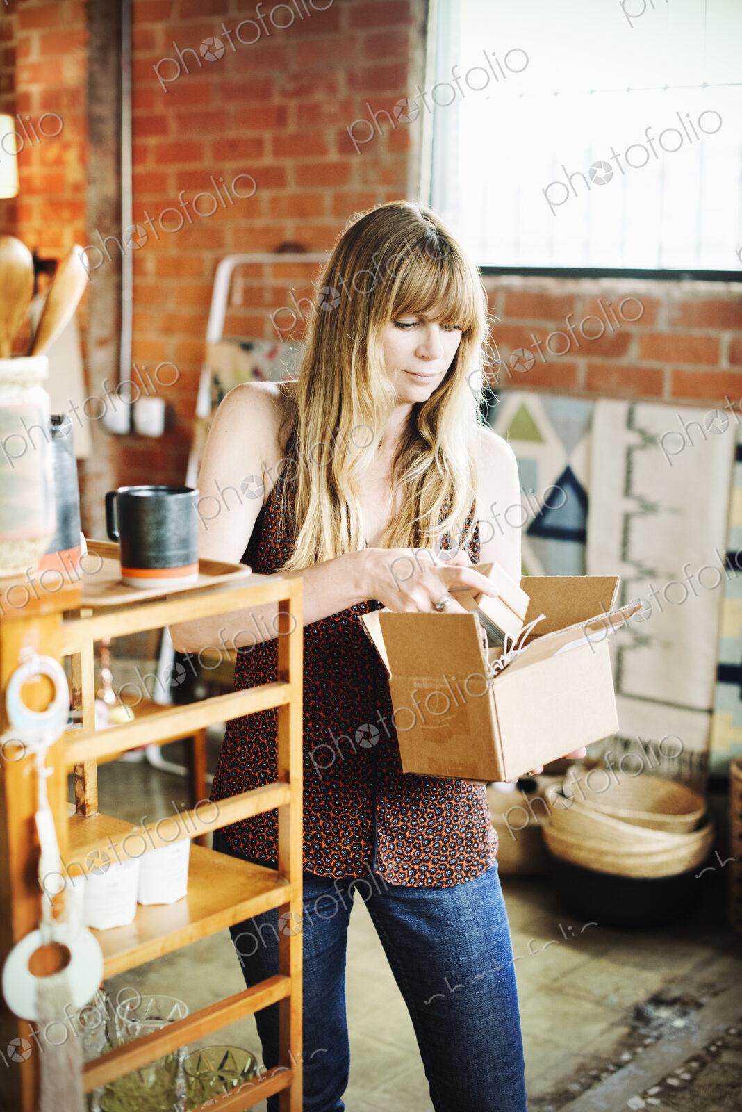 Woman in a shop, holding a small cardboard box with merchandise.