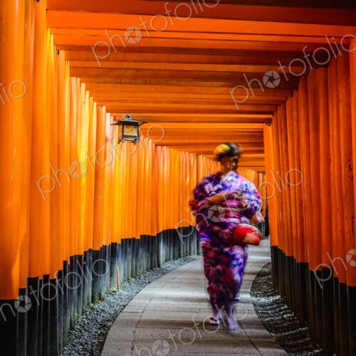 Woman in kimono walking under wooden pillars Woman in kimono walking under wooden pillars