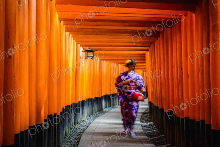 Woman in kimono walking under wooden pillars