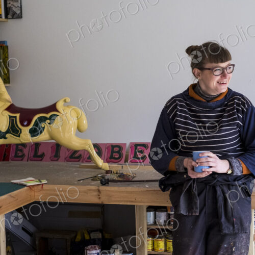 Woman in workshop next to traditional wooden carousel galloper horse from merry-go-round. Woman in workshop next to traditional wooden carousel galloper horse from merry-go-round.
