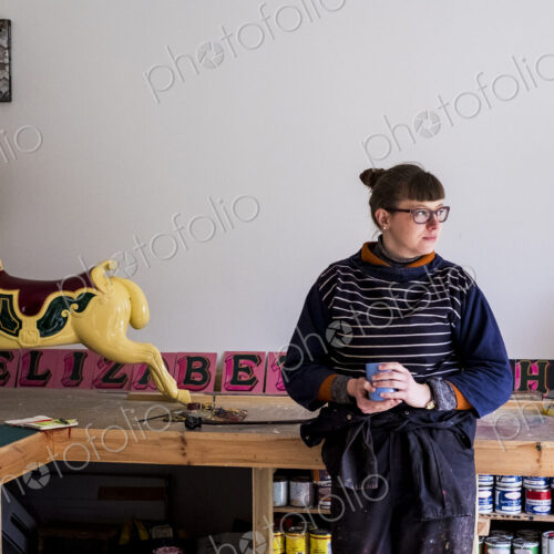 Woman in workshop with a traditional wooden carousel horse from merry-go-round.