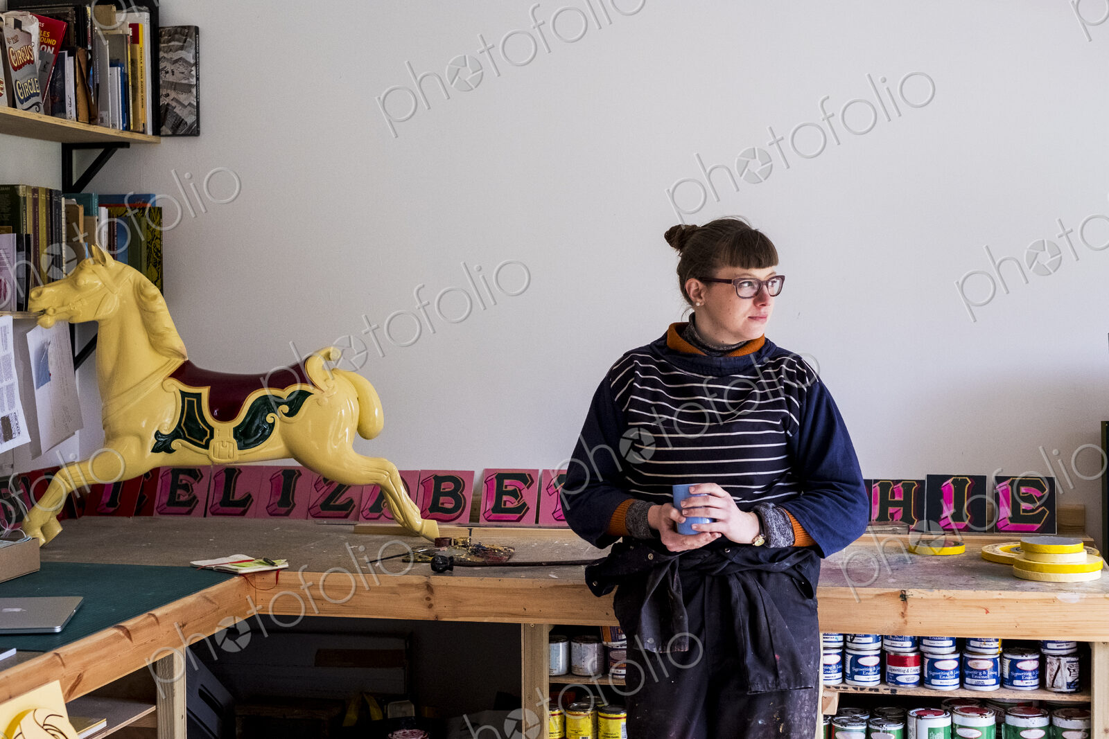 Woman in workshop with a traditional wooden carousel horse from merry-go-round.