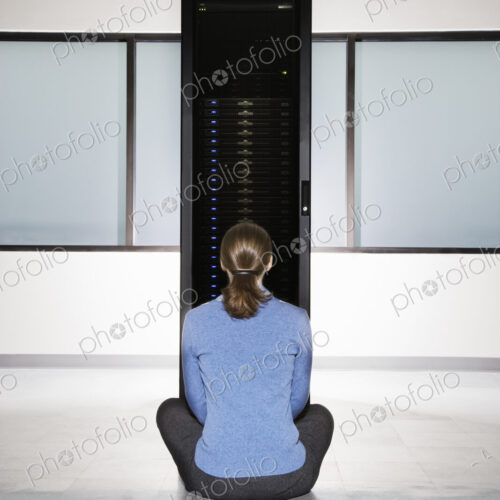 Woman lab technician sitting in front of a rack for servers in a computer server farm. Woman lab technician sitting in front of a rack for servers in a computer server farm.