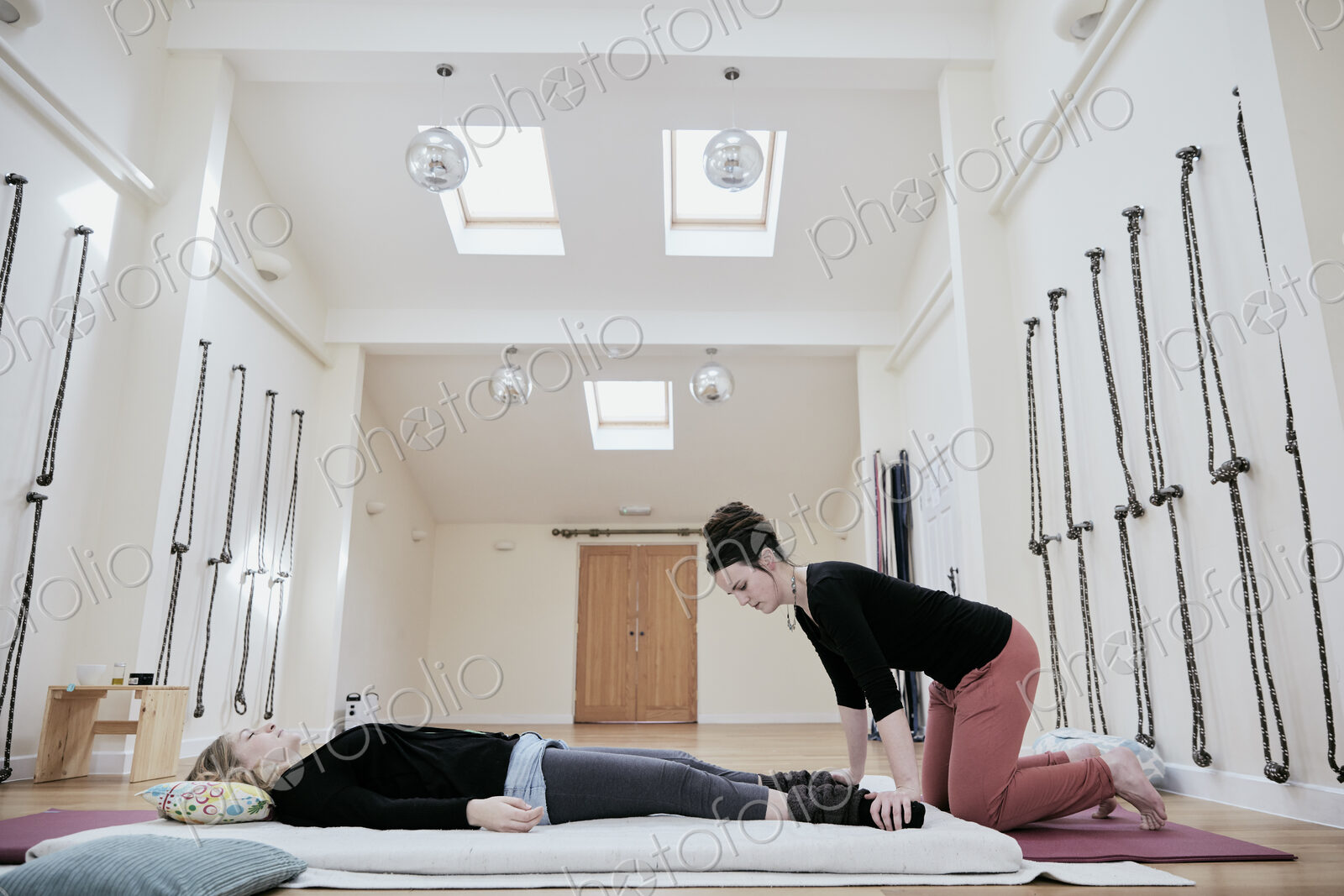 Woman lying down fully clothed having a Thai massage in a light filled exercise studio