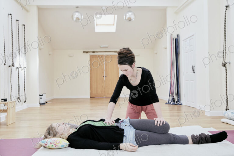 Woman lying down having a Thai massage, a masseur stretching her legs and knee joints.