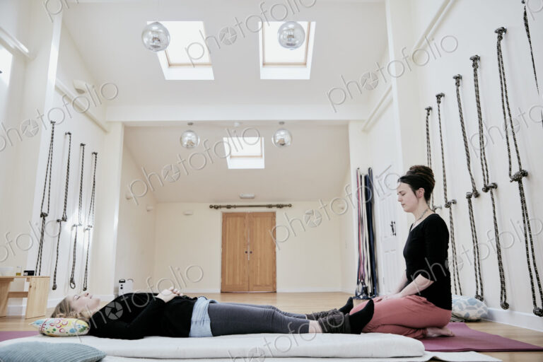 Woman lying down on her back fully clothed in preparation for a Thai massage