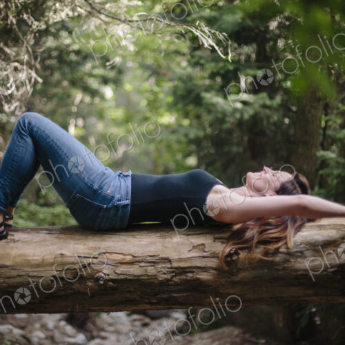 Woman lying on her back on a fallen tree trunk in a forest. Woman lying on her back on a fallen tree trunk in a forest.