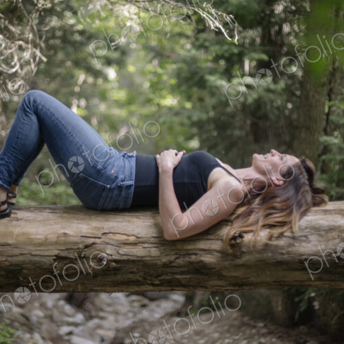 Woman lying on her back on a tree in a forest. Woman lying on her back on a tree in a forest.