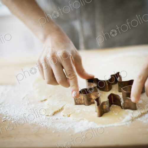 Woman making organic Christmas cookies, cutting dough with a cookie cutter.