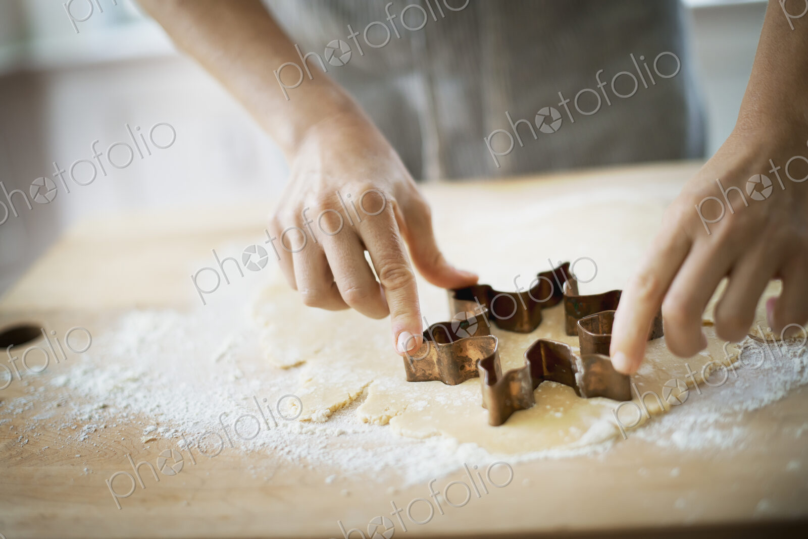 Woman making organic Christmas cookies, cutting dough with a cookie cutter.