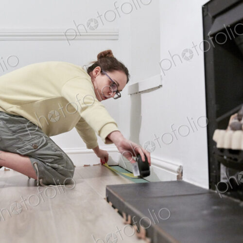 Woman measuring space fit new floor boards Woman measuring space fit new floor boards