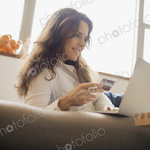 Woman on-line shopping on laptop on sofa with credit card Woman on-line shopping on laptop on sofa with credit card