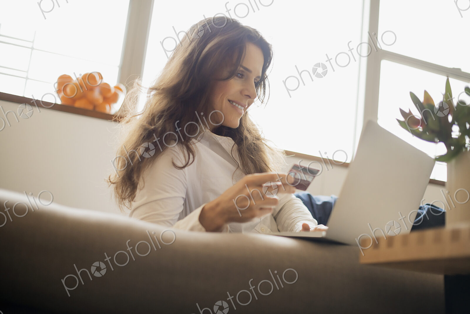 Woman on-line shopping on laptop on sofa with credit card