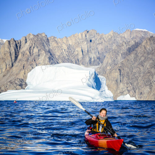 Woman paddling canoe near glaciers in remote river Woman paddling canoe near glaciers in remote river