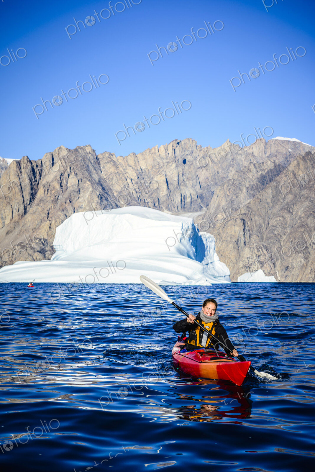 Woman paddling canoe near glaciers in remote river