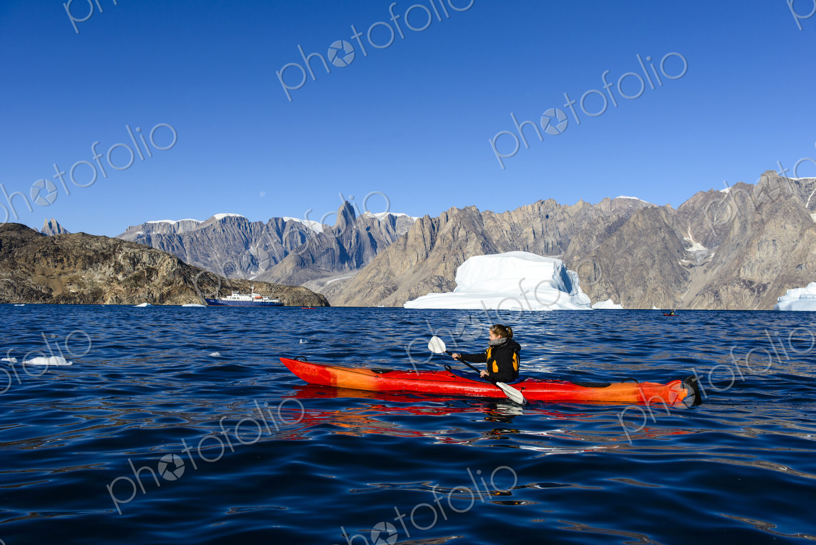 Woman paddling canoe near glaciers in remote river