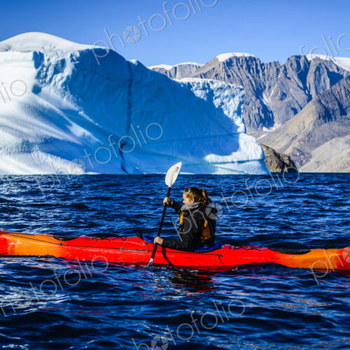 Woman paddling canoe near glaciers in remote river Woman paddling canoe near glaciers in remote river