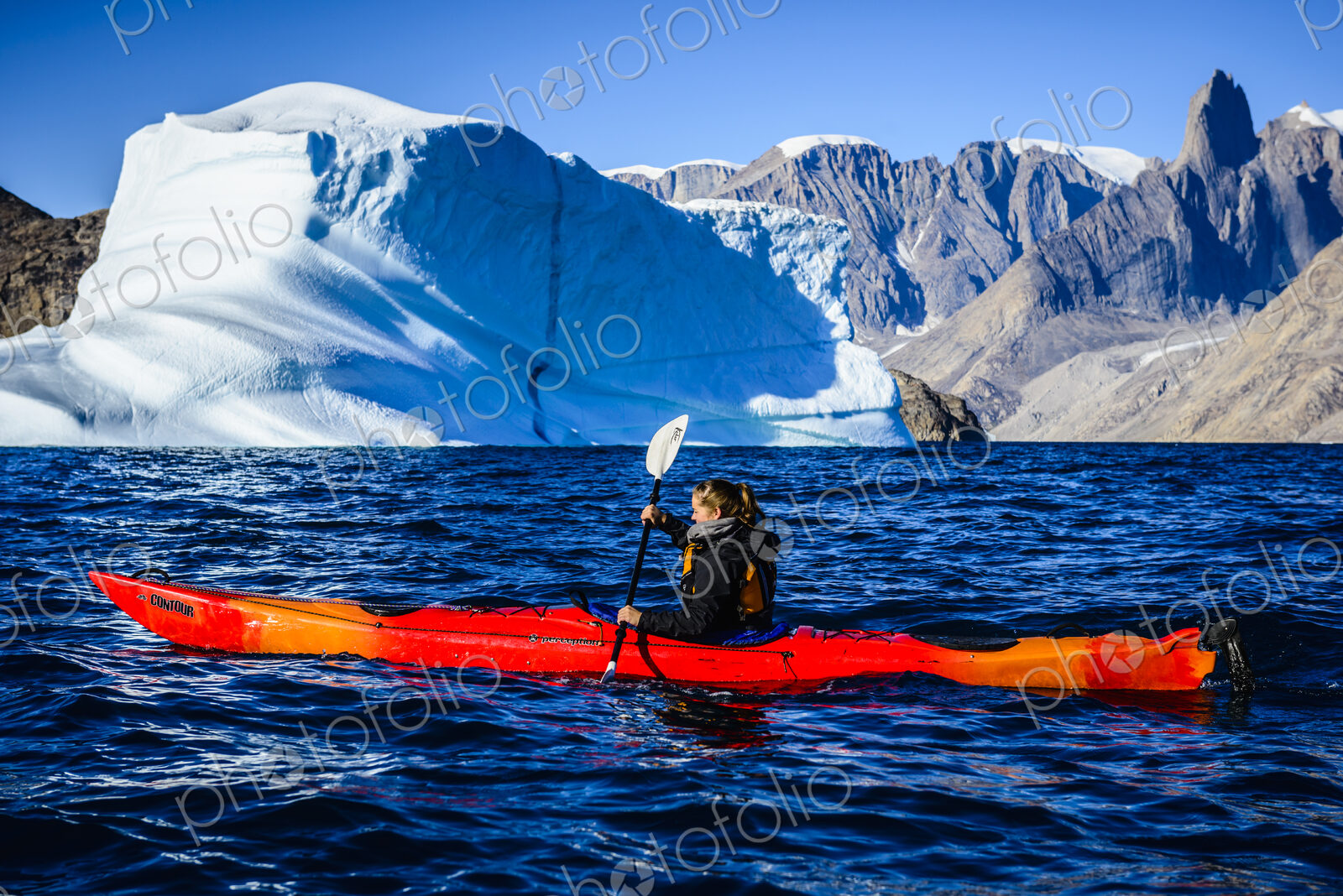 Woman paddling canoe near glaciers in remote river