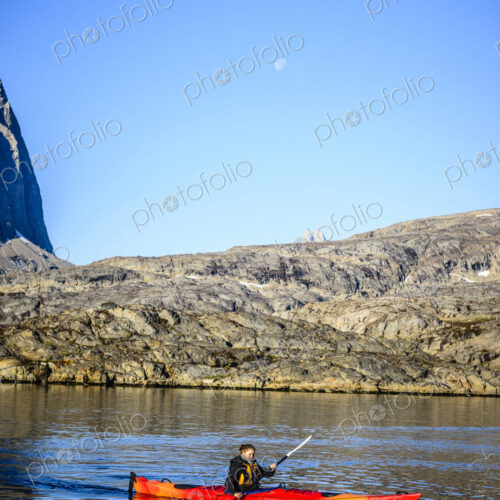 Woman paddling canoe near rock formations in remote river Woman paddling canoe near rock formations in remote river