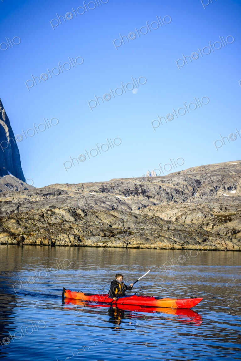 Woman paddling canoe near rock formations in remote river