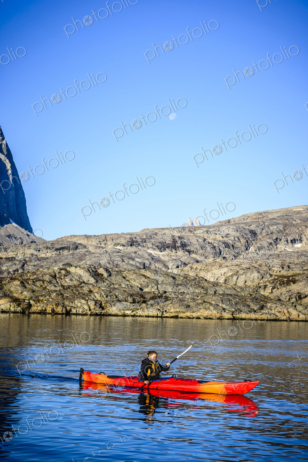 Woman paddling canoe near rock formations in remote river