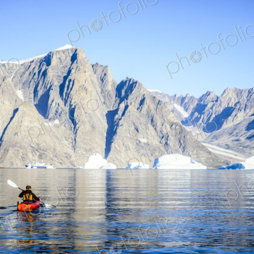 Woman paddling canoe towards glaciers in remote river Woman paddling canoe towards glaciers in remote river