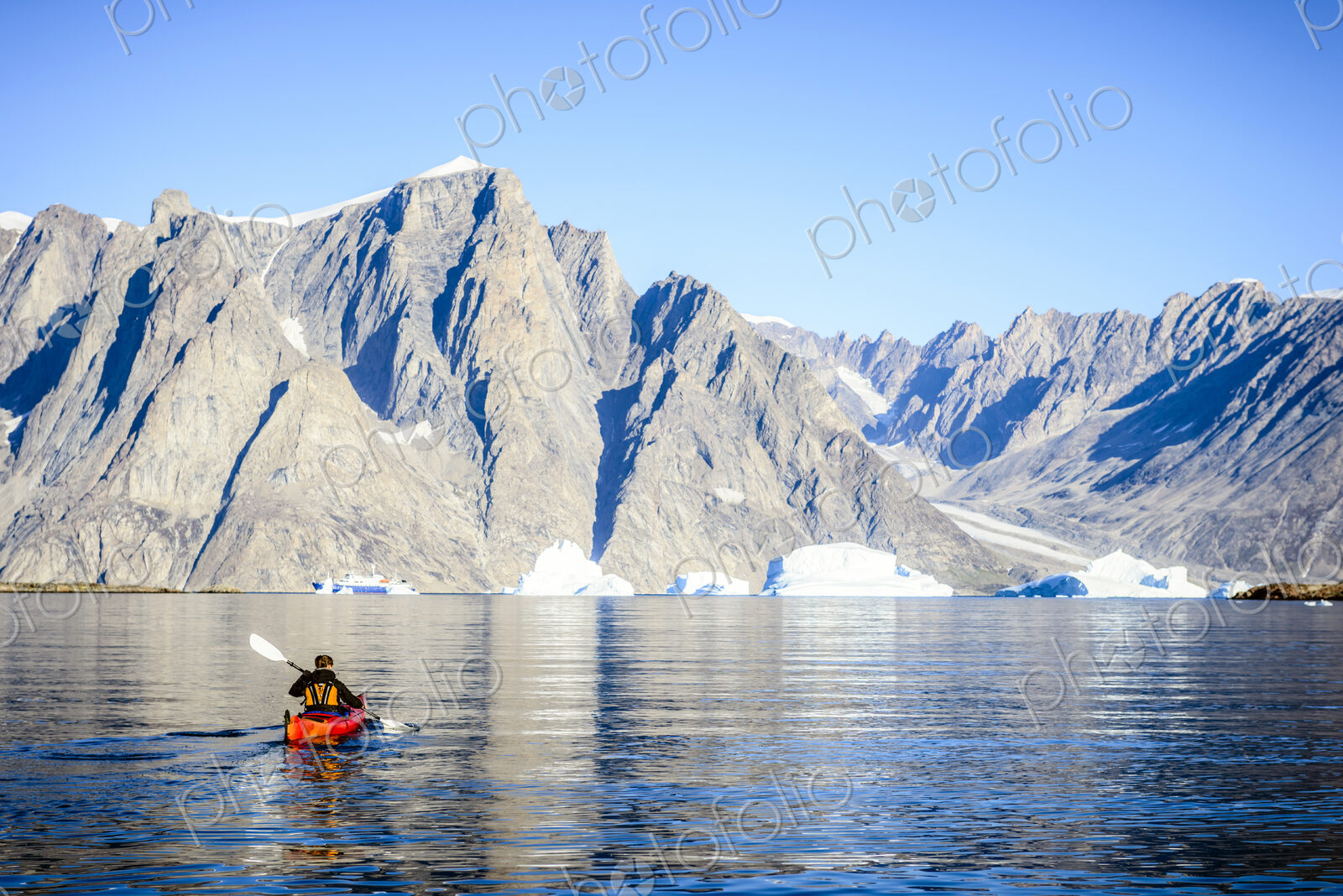 Woman paddling canoe towards glaciers in remote river