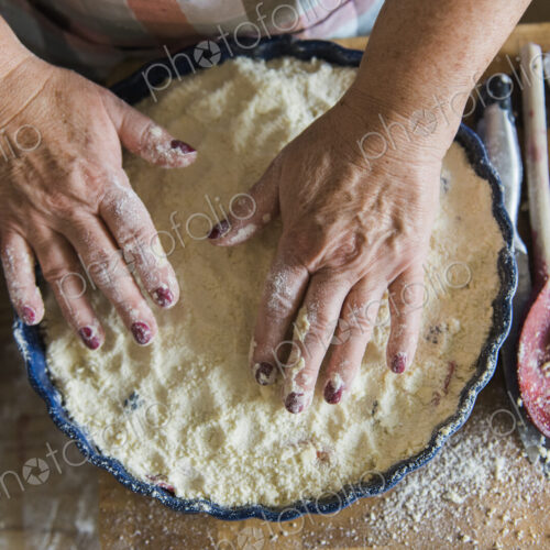 Woman patting crumble mixture into a pie dish, making a fruit crumble pudding. Woman patting crumble mixture into a pie dish, making a fruit crumble pudding.