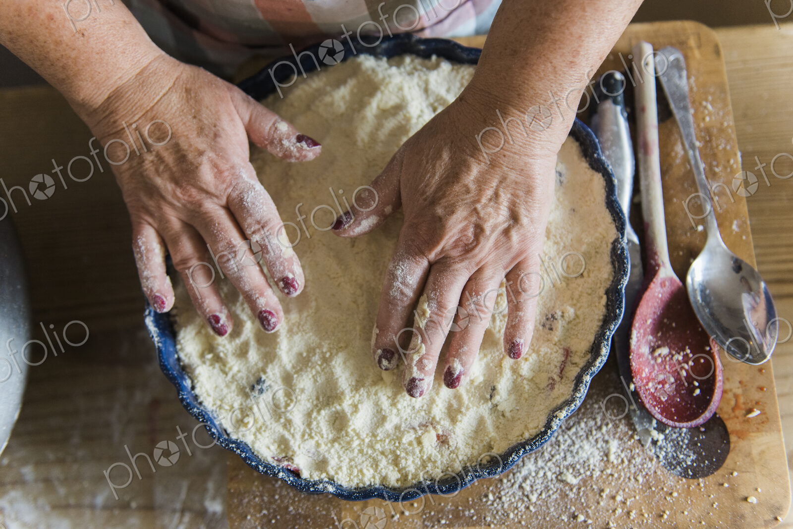 Woman patting crumble mixture into a pie dish, making a fruit crumble pudding.