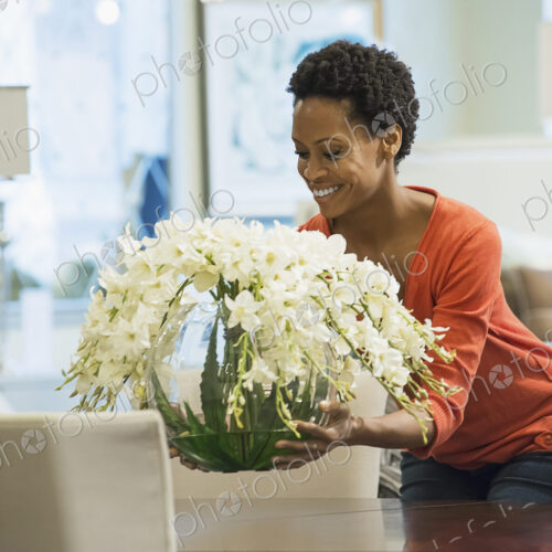 Woman placing vase of flowers on table Woman placing vase of flowers on table