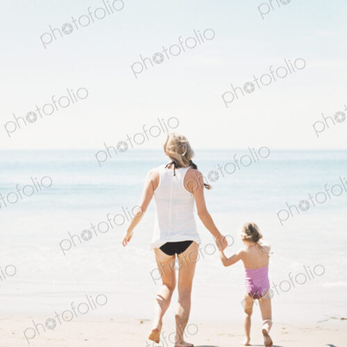 Woman playing with her daughter on a sandy beach.