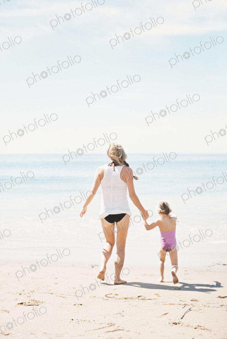Woman playing with her daughter on a sandy beach.