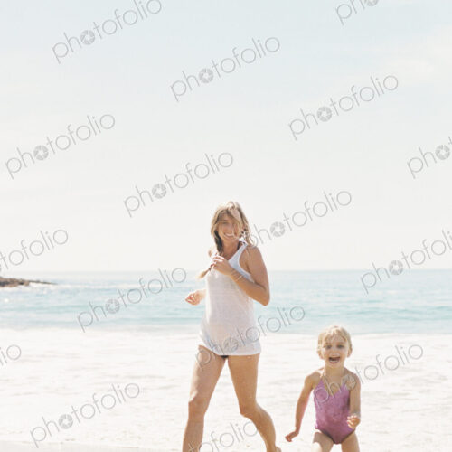 Woman playing with her daughter on a sandy beach.