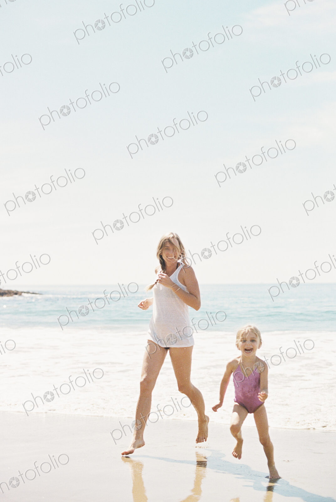 Woman playing with her daughter on a sandy beach.