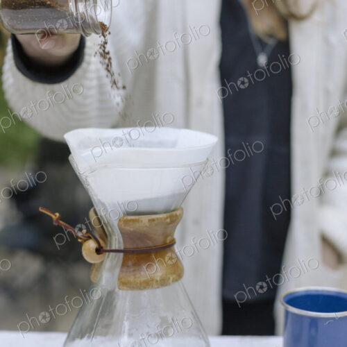 Woman pouring ground coffee from a jar into a glass coffee maker. Woman pouring ground coffee from a jar into a glass coffee maker.