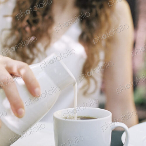 Woman pouring milk in a cup of tea.