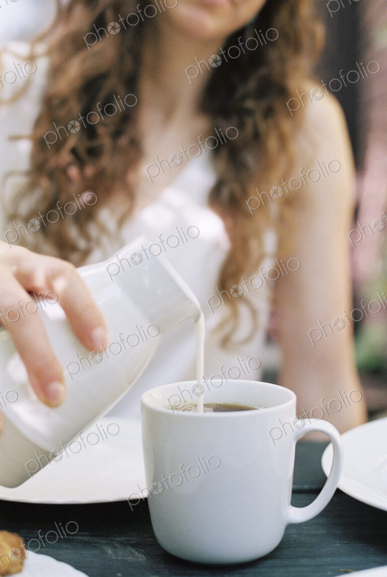 Woman pouring milk in a cup of tea.