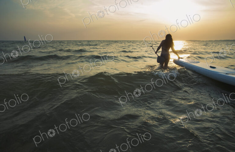 Woman pulling paddleboard in lake
