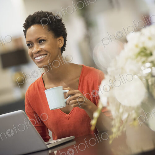 Woman relaxing at home with laptop and coffee
