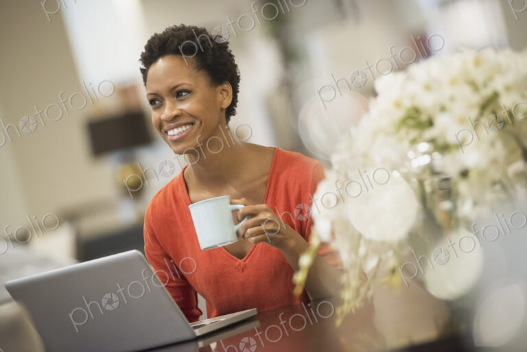 Woman relaxing at home with laptop and coffee